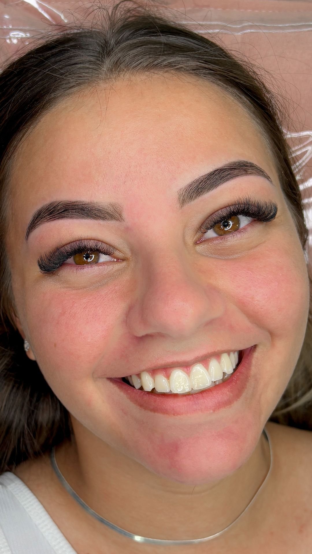 Cliente sorrindo depois da aplicação de extensão de cílios no estúdio
